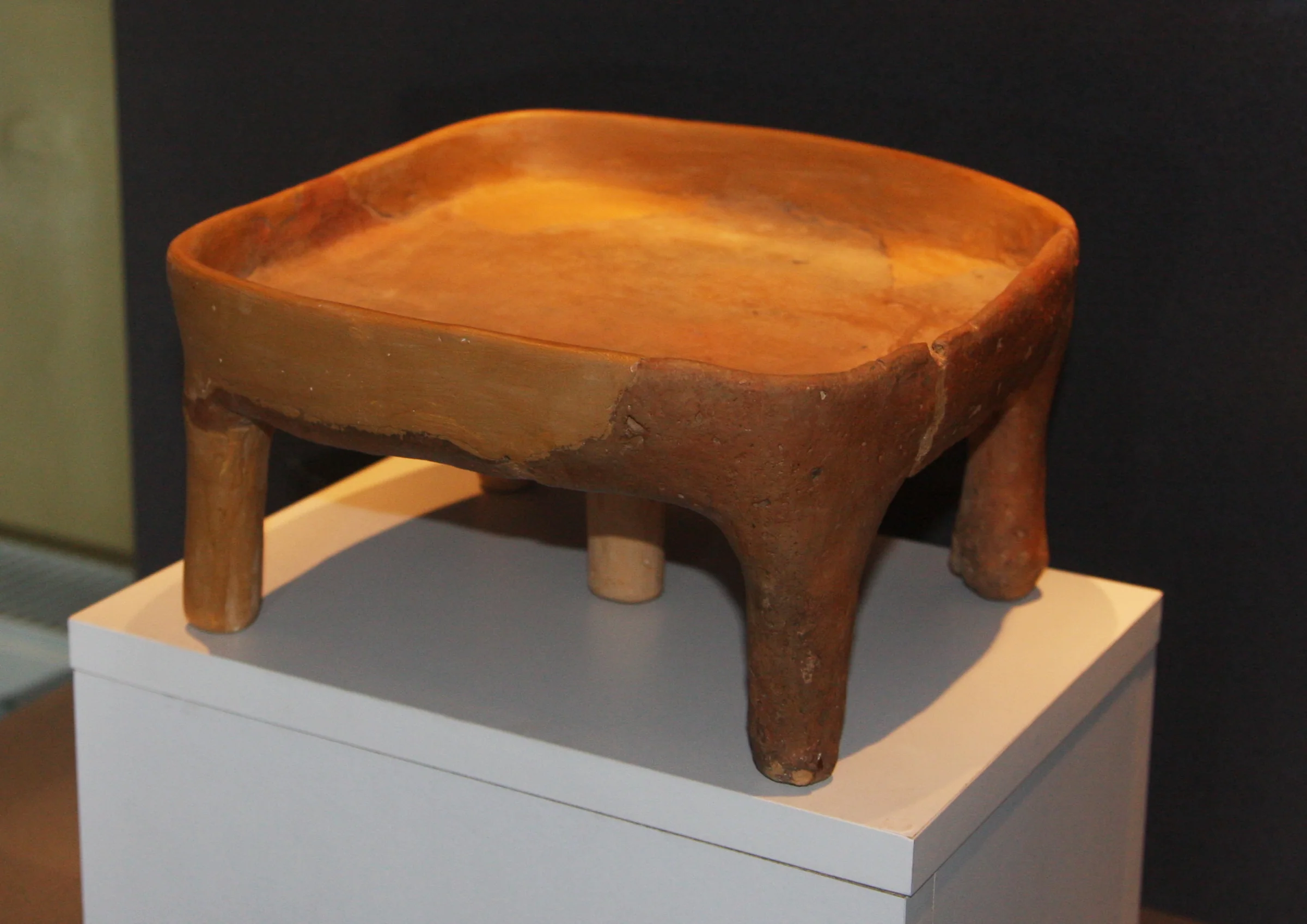 A four-legged ceramic object on a white plinth